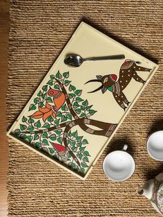 a ceramic cutting board sitting on top of a table next to cups and saucers