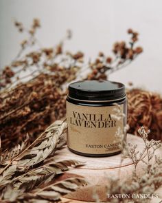 a candle sitting on top of a wooden table next to dried flowers and plants in the background