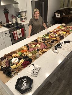 a woman standing in front of a table full of food on top of a kitchen counter