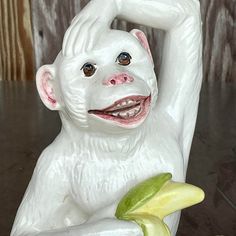 a white monkey figurine holding a banana