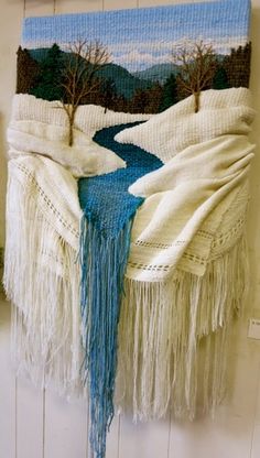 a blanket hanging on the wall next to a wooden door with a river running through it