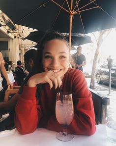 a woman sitting at a table with a drink in front of her