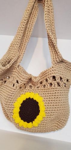 a crocheted bag with a sunflower on the front and bottom, hanging from a hook