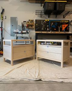 two wooden dressers sitting on top of a sheet in a room filled with tools