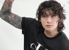 a young man with tattoos on his arms and shoulder is posing for the camera while wearing a black tshirt