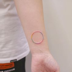 a person's arm with a small rainbow tattoo on the left side of their wrist