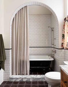 a bath room with a toilet a tub and a shower curtain on the side of it