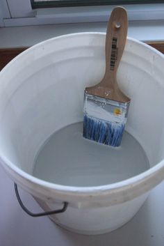 a paintbrush in a white bucket with water