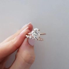 a woman's hand holding an engagement ring with two diamonds on top of it