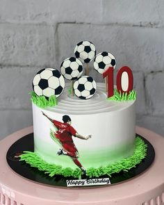 a birthday cake with soccer balls on top and the number ten is decorated to look like a soccer player