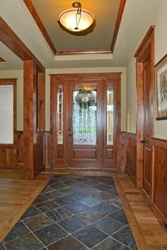 an entry way with wood paneling and glass doors on both sides, surrounded by tile flooring