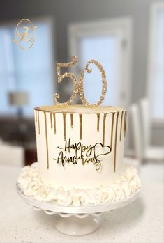 a white and gold cake with the number 50 on it's top sitting on a table