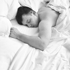 black and white photograph of man sleeping in bed