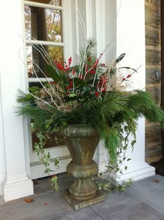 a large vase filled with lots of flowers on top of a stone floor next to a door