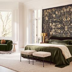 a bedroom with a large tapestry on the wall above the bed and two chairs in front of it