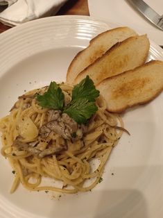 a white plate topped with pasta and sliced bread