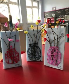 three vases with flowers in them sitting on a red counter top next to each other