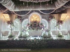 an elaborately decorated stage with white chairs and flowers