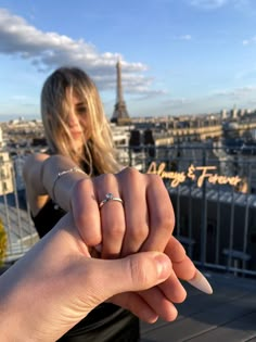 a woman holding onto her engagement ring in front of the eiffel tower, paris