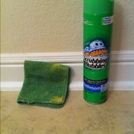 a bottle of mouthwash next to a green towel and microfiber cloth on the floor