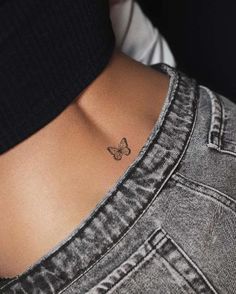 a small butterfly tattoo on the back of a woman's left ribcage