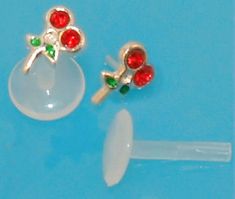 two red and green earrings sitting on top of a white piece of plastic next to each other