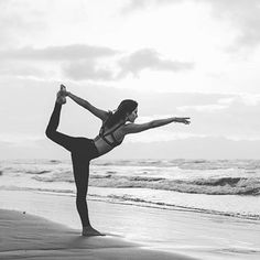 a woman is doing yoga on the beach