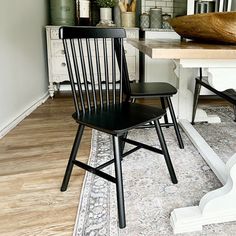 two black chairs sitting on top of a wooden floor next to a white table and chair