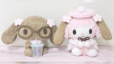 two stuffed animals sitting next to each other on a pink blanket with a drink in front of them