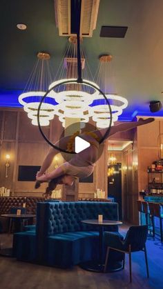 a woman is suspended upside down in the middle of a room with chairs and tables