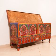 an elaborately painted chest on wheels sits in a room with tile flooring and white walls