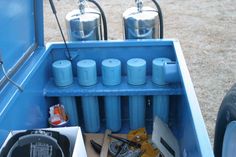 the back end of a blue truck filled with gas cans