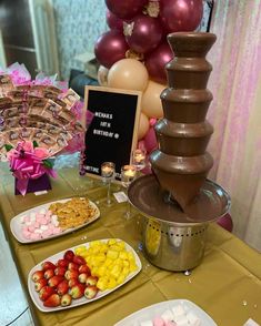 a table topped with lots of food and desserts next to a tall chocolate fountain