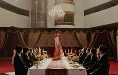 a group of people sitting at a table in front of a woman dressed in a wedding dress