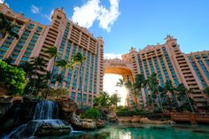 the hotel is next to a waterfall in front of some palm trees and other buildings