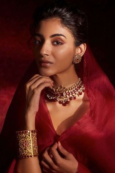 a woman in a red dress with gold jewelry