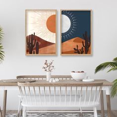 two paintings hang on the wall above a dining room table with white chairs and a cactus plant