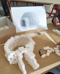 a man is making an igloose out of foam blocks on a table