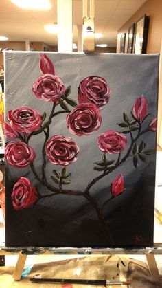 a painting with red roses on it is being displayed in an art class or studio