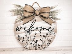 a welcome sign hanging on the side of a brick wall with a bow around it