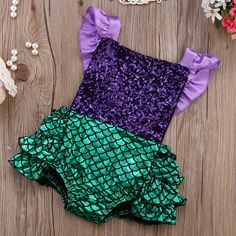 two pieces of purple and green sequins on a wooden surface