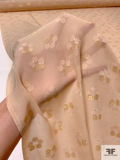 a close up of a person's hand holding a piece of fabric with gold dots on it