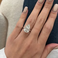 a woman's hand with a diamond ring on her left hand and the other hand holding an engagement ring