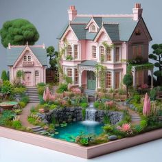 a model of a pink house with a waterfall in the front yard and lots of greenery surrounding it