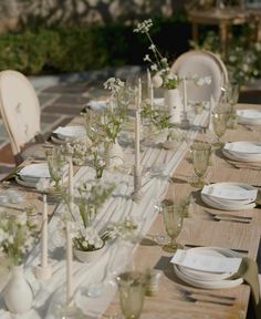 a long table with white plates and vases on it