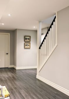 an empty room with hard wood flooring and white railings on the wall next to stairs