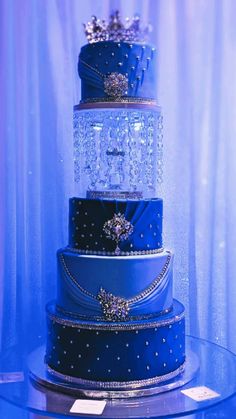 a three tiered cake with blue frosting and silver decorations on it's sides