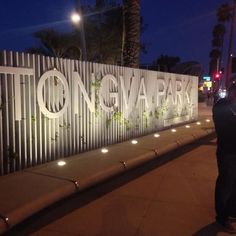 a man standing next to a white fence on the side of a road at night