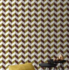 a chair and table in front of a wall with geometric patterns on it, next to a small side table