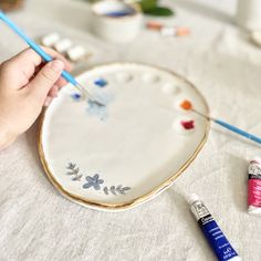 someone is painting a heart on a plate with paint and crayons next to it